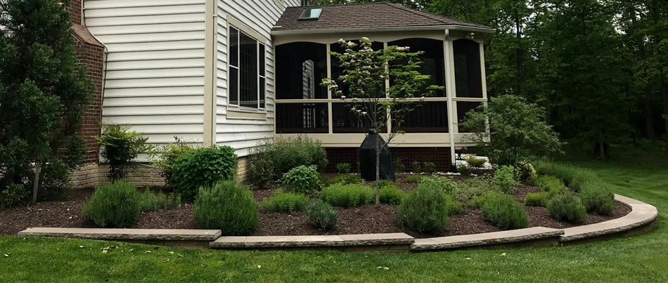 A backyard landscape in Bristow, VA, full of plants with a retaining wall.